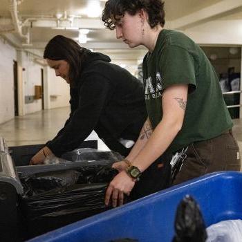 2 recycling employees changing bags of waste bins 